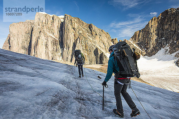 Rucksacktouristen überqueren mit dem Seil einen Gletscher auf Baffin Island.