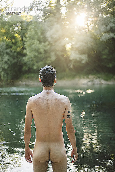 Rückenansicht eines nackten Mannes am Fluss