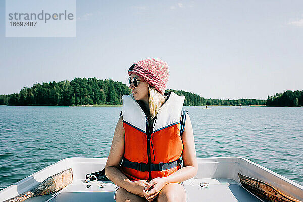 Frau sitzt friedlich in einem Ruderboot im Sommer auf einem See