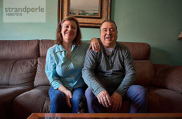 Ein Paar mittleren Alters posiert und lächelt für ein Foto zu Hause