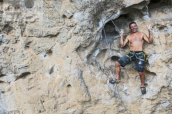 Mann lächelt für den Fotografen beim Klettern an einer Felswand in China