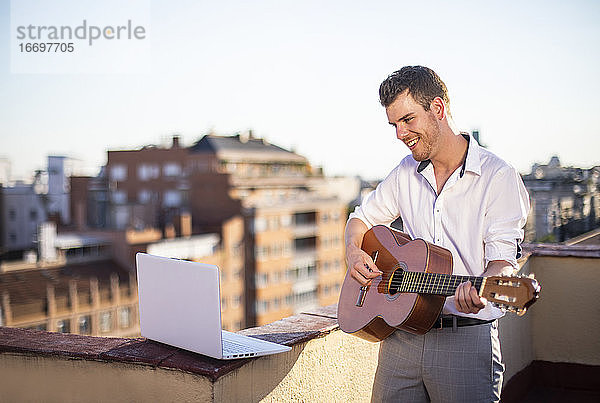 gut aussehender junger Sänger  der während der Quarantäne vom Dach seines Hauses aus für seine Fans in den sozialen Medien auftritt