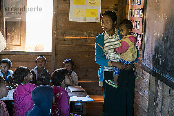 Lehrerin mit Baby an der Tafel beim Unterricht in der Grundschule im Dorf Kayan  Loikaw  Myanmar