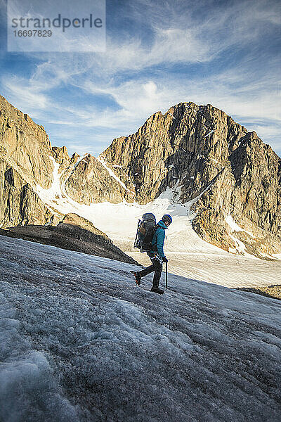 Rucksacktourist beim Abstieg von einem Gletscher  umgeben von Bergen.