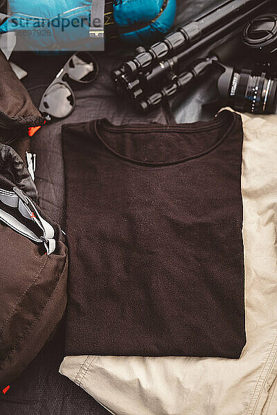 Schwarzes T-Shirt in einem Zelt  umgeben von Foto- und Campingausrüstung