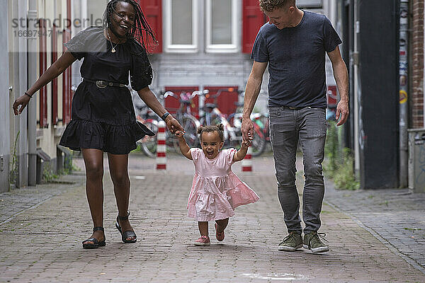 Eine gemischtrassige Familie geht mit ihrer kleinen Tochter durch die Stadt