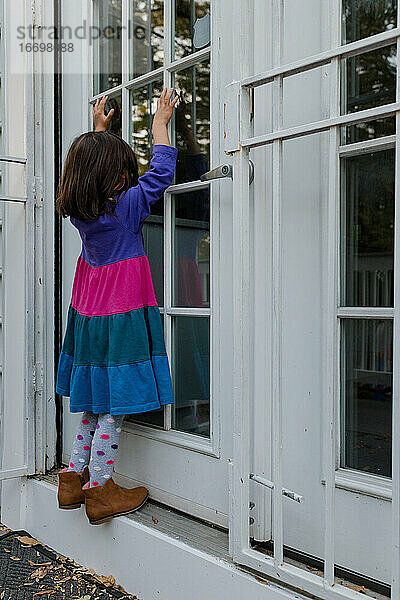 Kleines Mädchen wartet ungeduldig an der Tür im Kleid