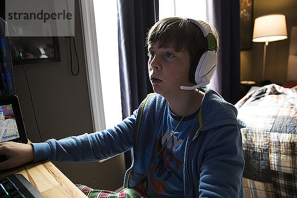 Nahaufnahme eines Teenagers  der Kopfhörer trägt und einen Computer spielt