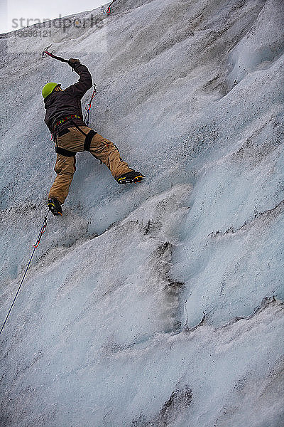 junger Mann klettert an der Eiswand des Solheimajokull-Gletschers in Island