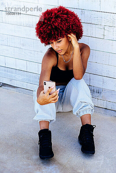 Frau mit rotem Afro-Haar macht ein Selfie mit Handy.