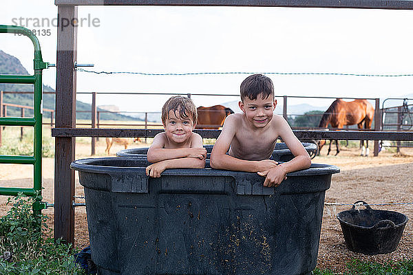 Kinder machen lustige Gesichter  während sie in einer Pferdetränke sitzen