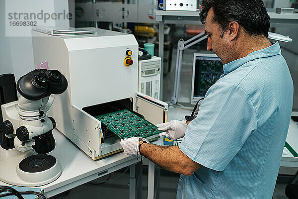 Mann führt Platte in Maschine und Mikroskop ein