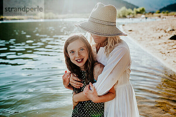 Mutter und Tochter  die sich umarmen und lächeln  während sie in einem See stehen