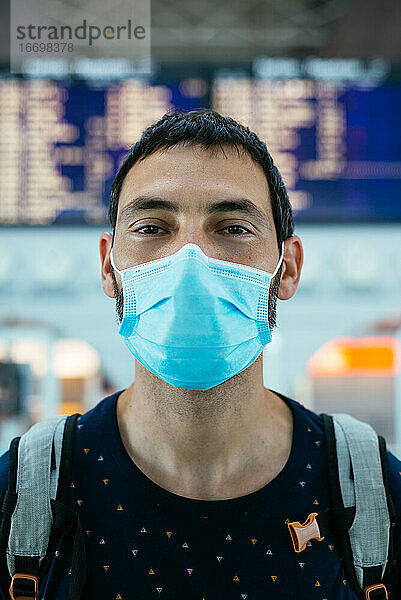 Porträt eines jungen Mannes mit einer Gesichtsmaske auf dem Flughafen