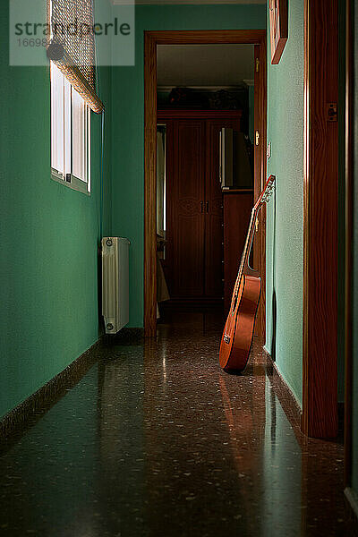 Eine Gitarre lehnt an der Wand eines Flurs in einem Haus