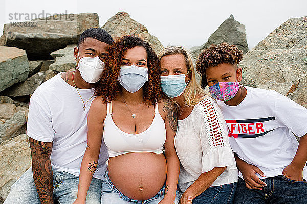 Familie mit Masken posiert auf Felsen am Strand