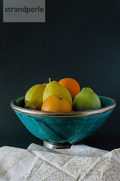 Türkisfarbene Schale mit erfrischenden Zitrusfrüchten  Orange  Zitrone und Limette.