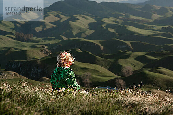 Junges Kind mit Blick auf grüne Berge in Neuseeland