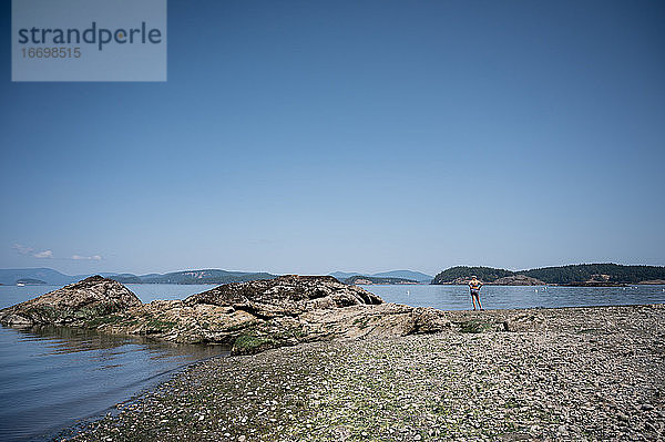 Junges Mädchen steht am Ufer und blickt auf das Meer auf Lopez Island WA