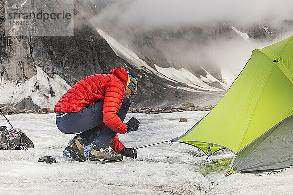 Bergsteiger schlägt sein Zelt auf dem Gletscher am Akshayak-Pass auf.