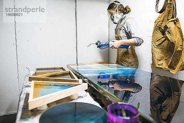 Weibliches Harz bei der Arbeit in einem selbstgebauten Studio mit einem Schweißbrenner