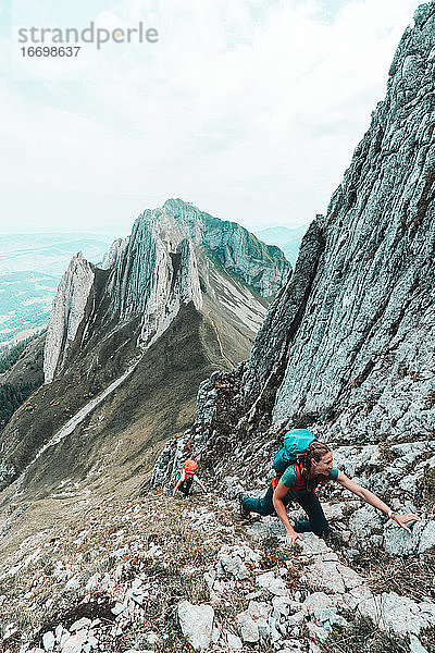 Zwei junge Frauen klettern in einem steilen Felscouloir in den Schweizer Alpen