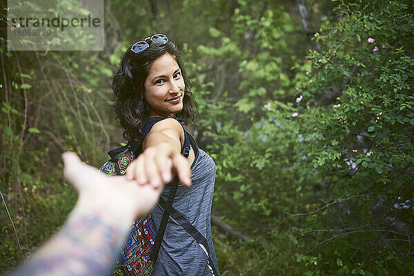 Porträt einer glücklichen jungen Frau  die die Hand ihres Freundes hält  während sie den Berg hinuntergeht