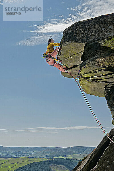 Frau beim Klettern an den Windgather-Felsen im britischen Peak District