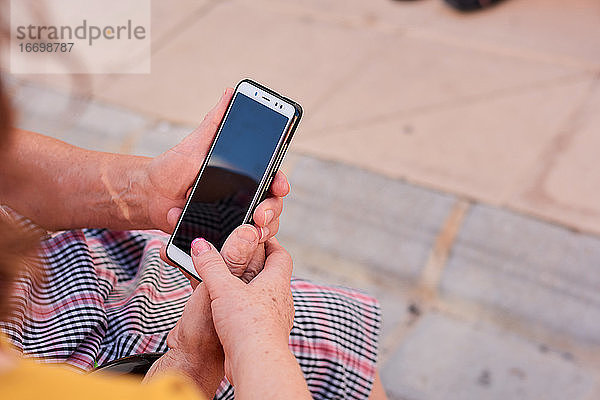Nahaufnahme einer Frau mittleren Alters und ihrer Mutter  die ein Smartphone halten