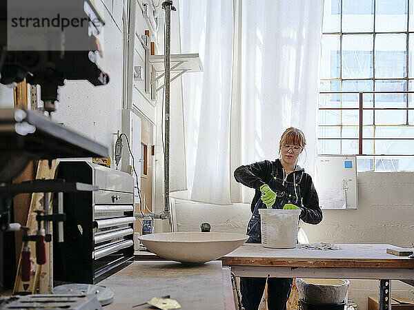 Professionelle Bildhauerin beim Mischen von Gips in ihrem Atelier