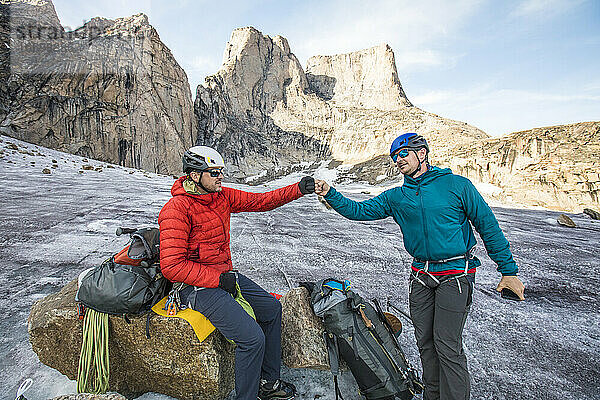 Zwei Bergsteiger stoßen sich nach erfolgreicher Besteigung unten am Berg die Faust an