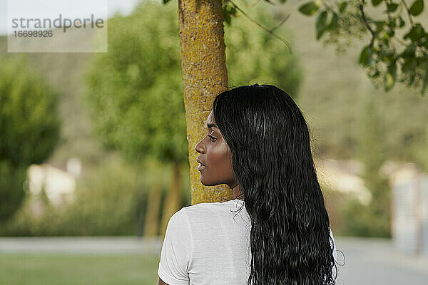 Schöne schwarze Frau schaut zur Seite in einem Park