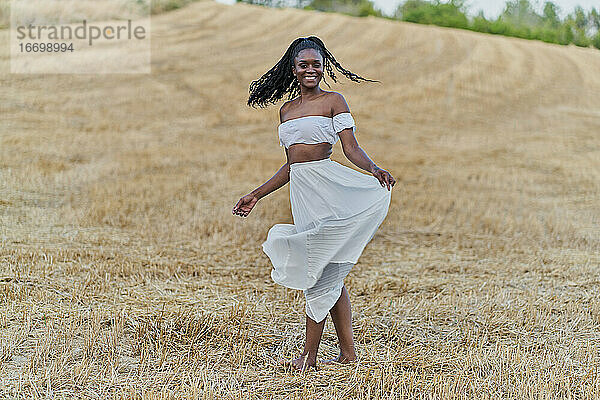 Fotosession einer schönen schwarzen Frau in einem Weizenfeld mit einem weißen Kleid