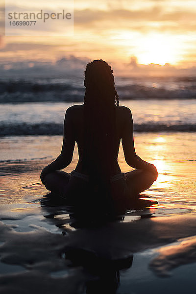 Silhouette einer Frau beim Yoga bei Sonnenuntergang