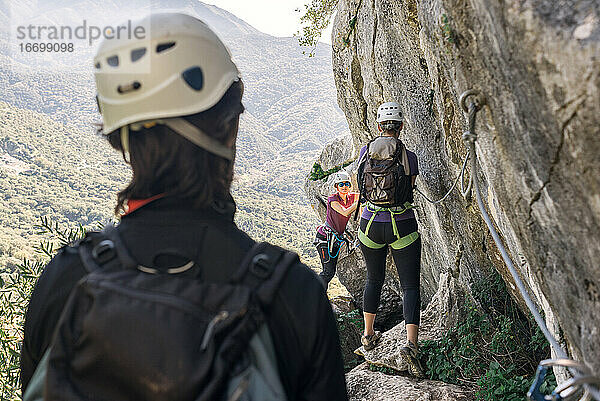 Konzept: Abenteuer. Zwei Frauen und ein Mann in den Bergen mit Helm  Klettergurt  Rucksack und Ausrüstung für den Klettersteig.