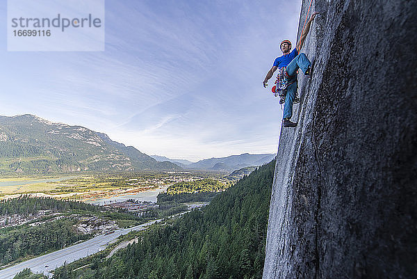 Mann beim Vorstieg auf Granit Squamish mit Blick auf das Tal im Hintergrund