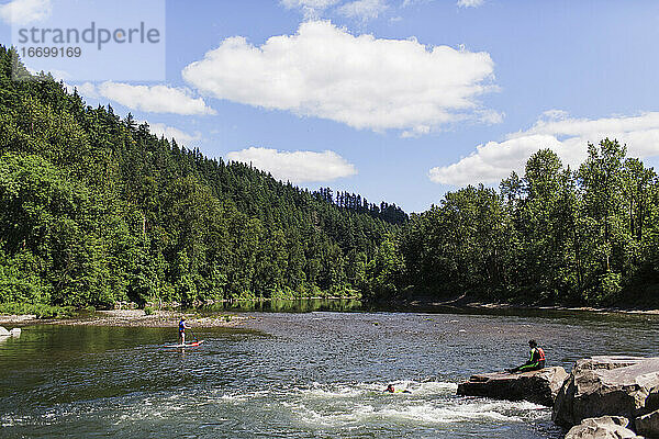 Junge Leute genießen einen ruhigen Fluss an einem Sommertag in Oregon.