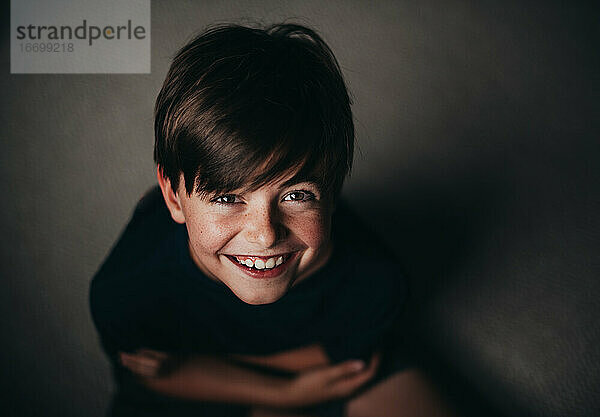 Porträt eines lächelnden Jungen mit Sommersprossen  von oben aufgenommen.