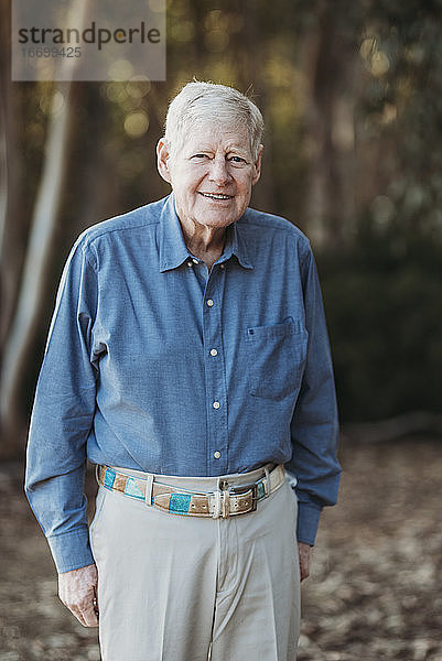 Porträt eines älteren erwachsenen Mannes  der im Wald lächelt
