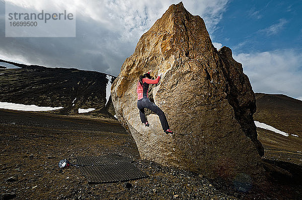 Frau beim Bouldern am Felsen im ländlichen Island