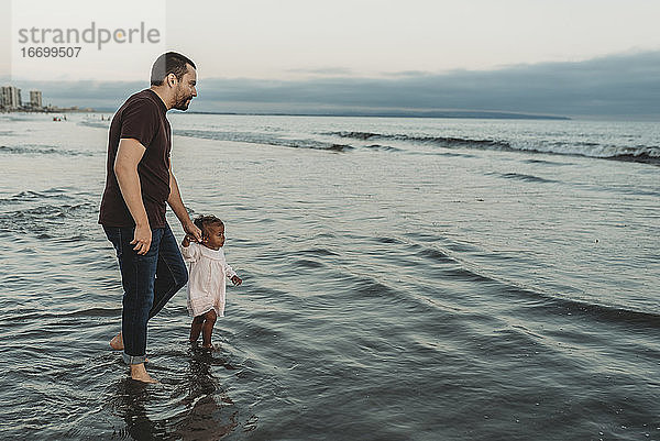 Kleine Tochter und junger Vater gehen ins Meer