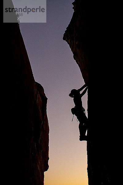 Schöne Aussicht auf die Silhouette eines kletternden Mannes bei Sonnenuntergang
