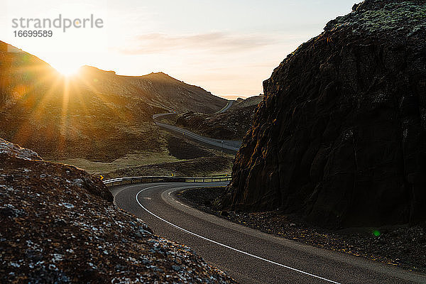 Kurvenreiche Straße inmitten von Felsen bei Sonnenuntergang