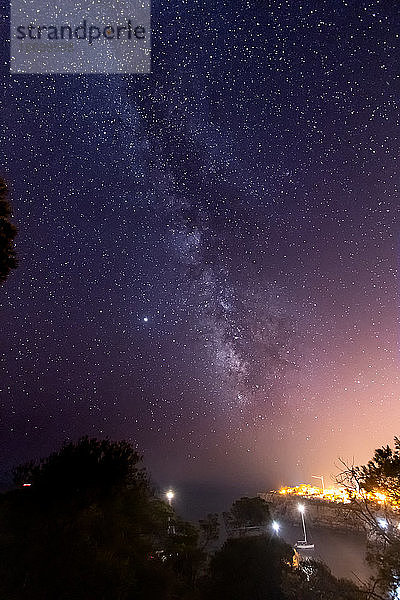Sternenklare Nacht mit der Milchstraße über einer kleinen Stadt und dem Meer  Mallorca