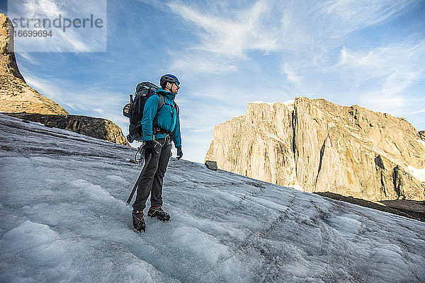 Rucksacktourist auf einem Gletscher unterhalb eines Berggipfels.