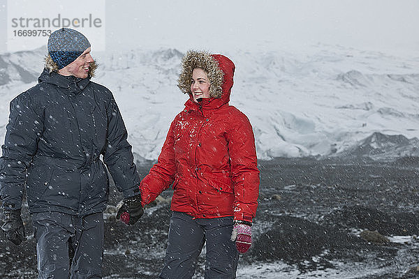 junges Paar bei einem Spaziergang durch einen Schneesturm in Island