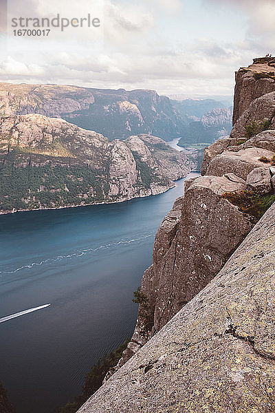 Blick von oben auf ein Boot  das durch Fjorde in Norwegen fährt