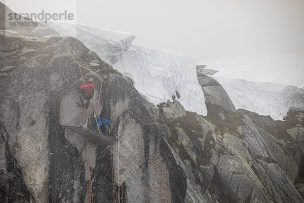 Kletterer benutzen ein Seil  um sich an der Portaledge an der Felswand abzuseilen.