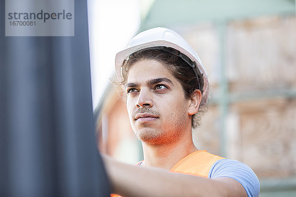 junger Angestellter mit Helm bei der Arbeit in einem Geschäft