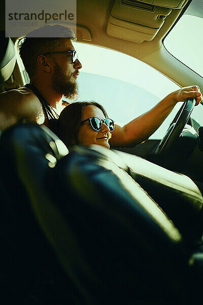 Eine Frau und ein Mann fahren im Sommer in einem Auto.